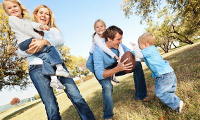 A family posing for photos in an outdoor setting while also playing football