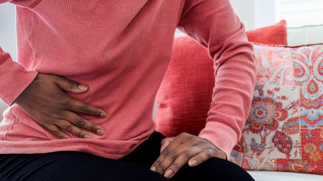 Close-up of Black woman's hand pressed against side of stomach