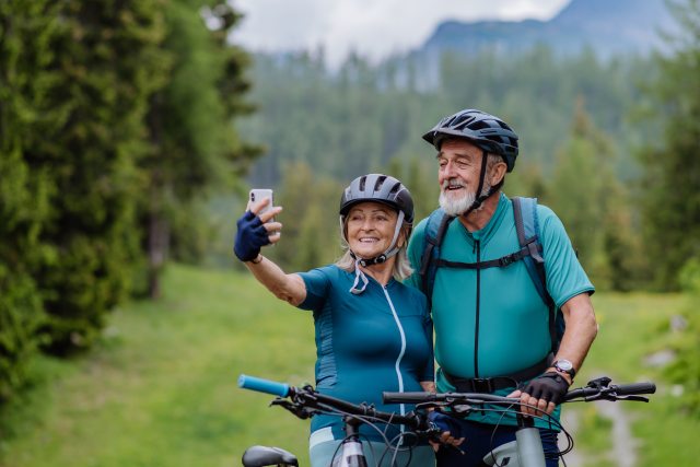 Woman uses cell phone to take selfie with an older man with bicycles