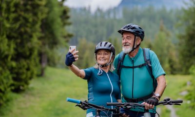 Woman uses cell phone to take selfie with an older man with bicycles