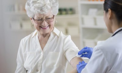 An elderly woman receives a vaccination in her left arm