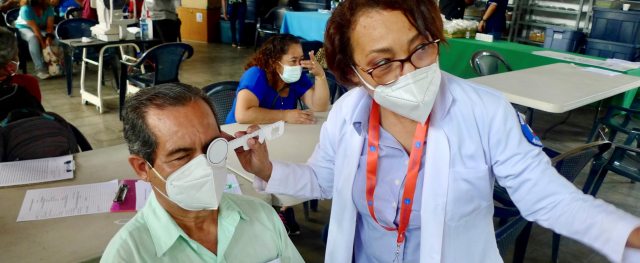 A PeaceHealth care provider examines the eyes of a PazSalud patient