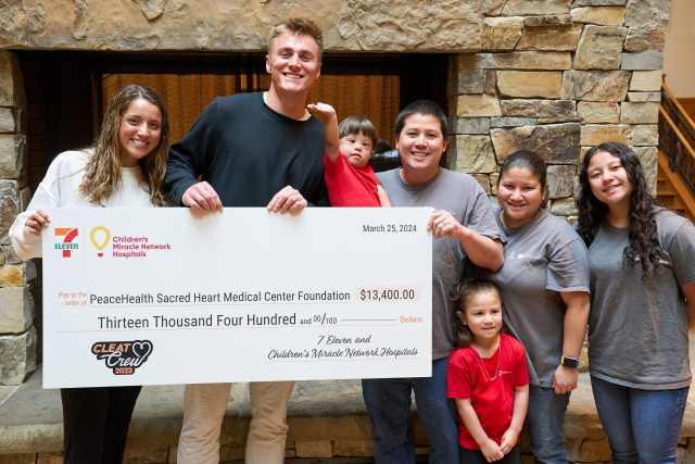 Quarterback Bo Nix, his wife, Izzy, and a local family who benefited from the Children's Miracle Network pose with a large check at PeaceHealth Sacred Heart Medical Center at RiverBend.