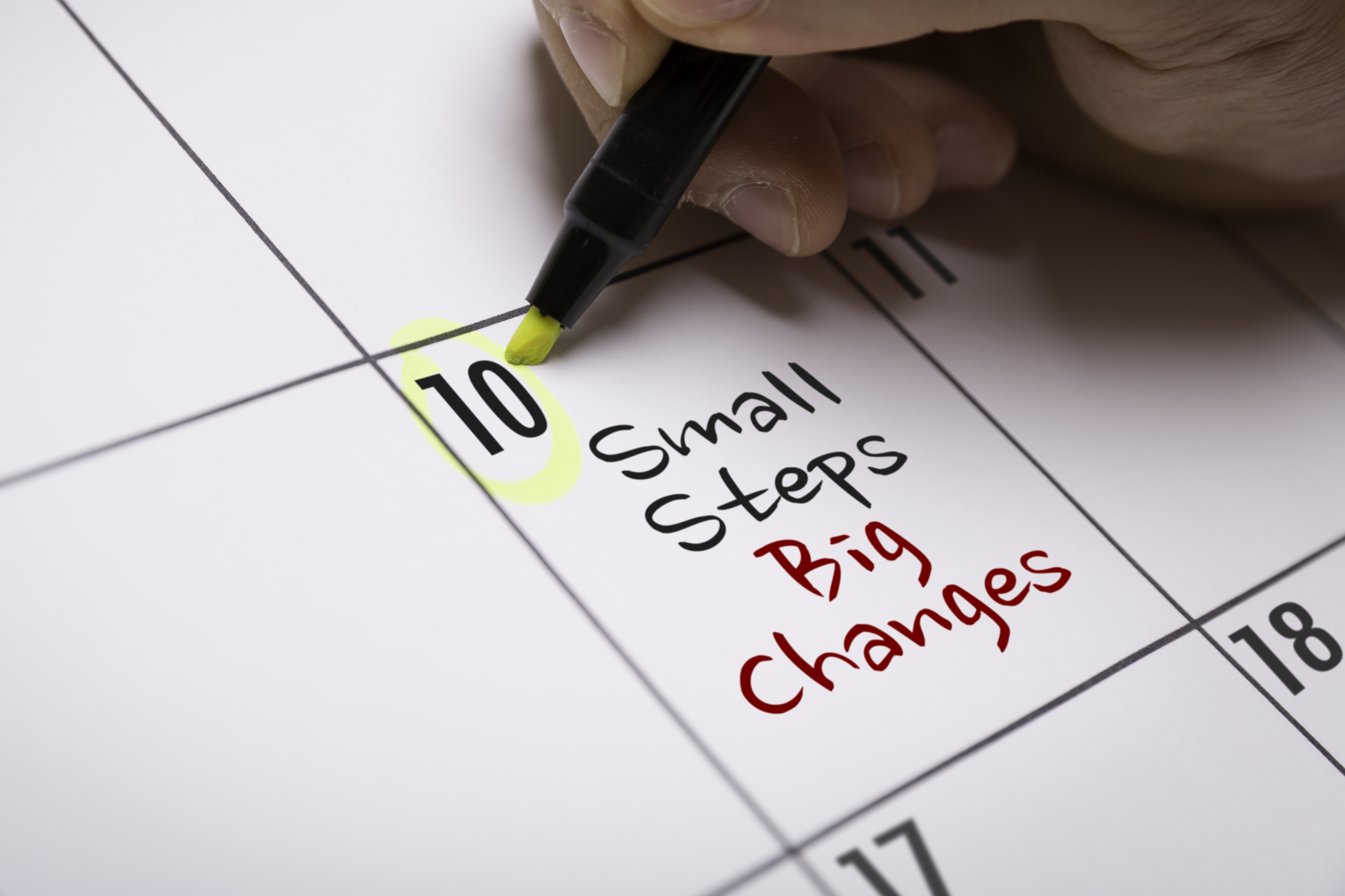 Close-up of a hand writing on a calendar the words "Small Steps Big Changes"