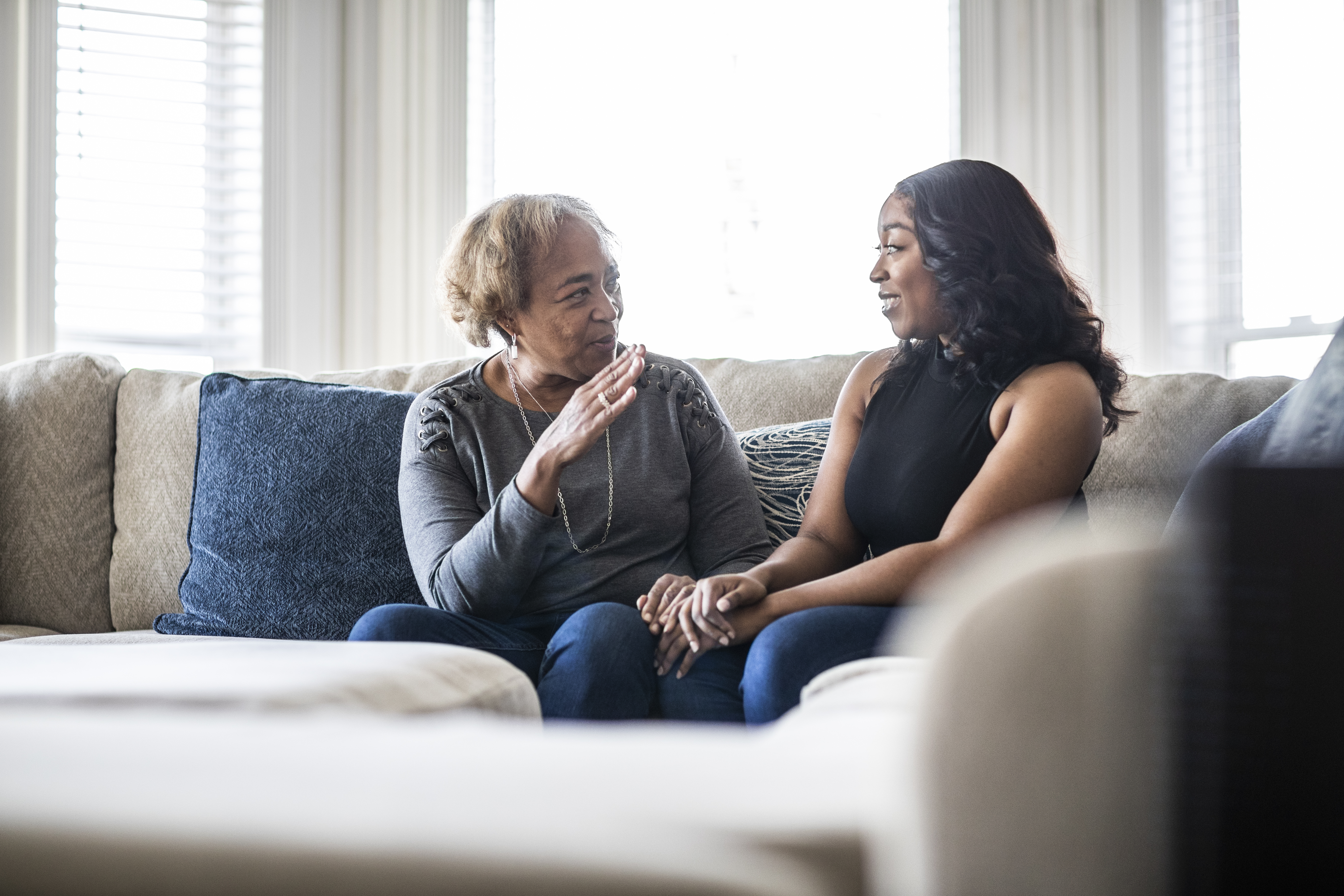 Two women sit and talk on a couch