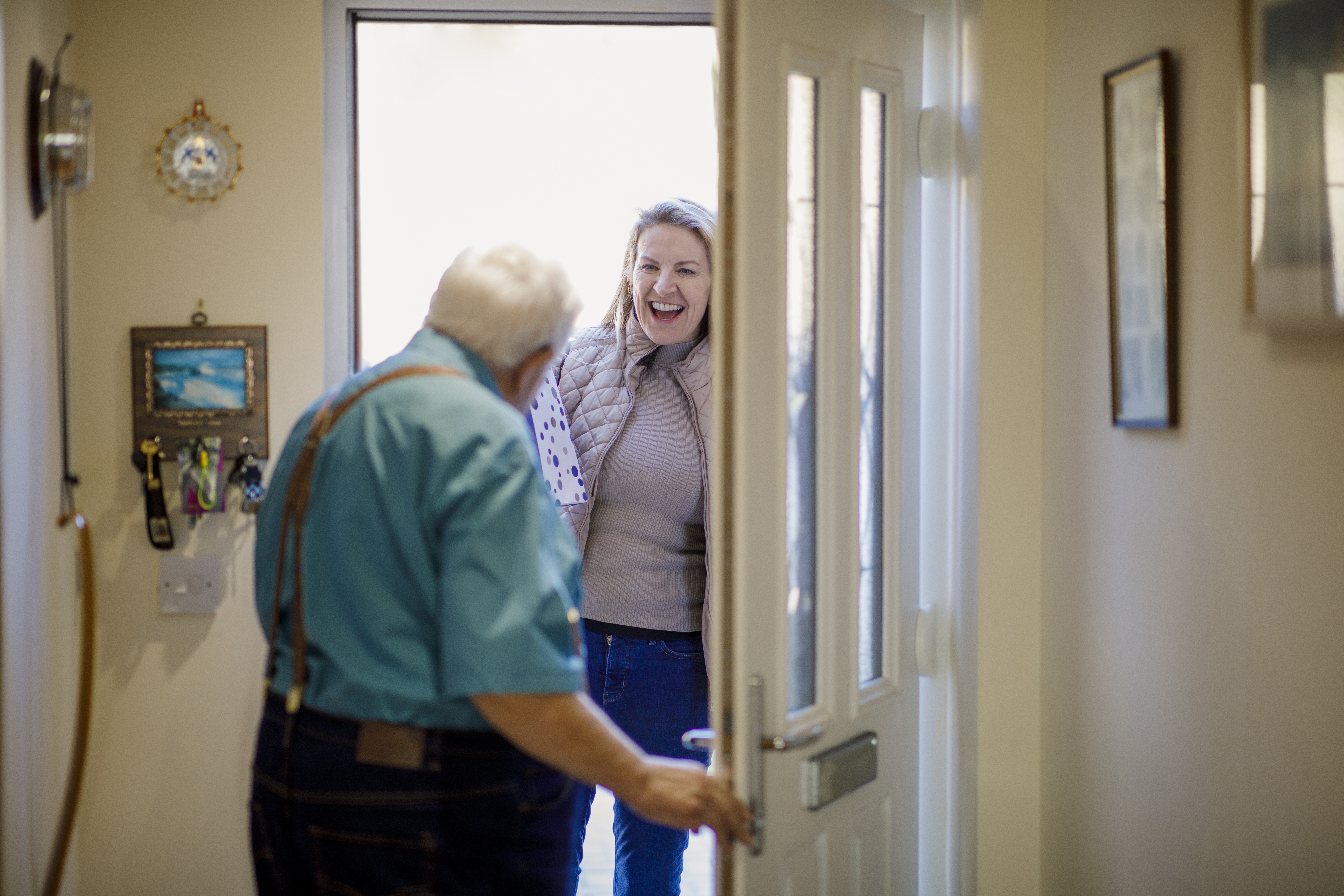 Older man opens door of his home to a happy woman