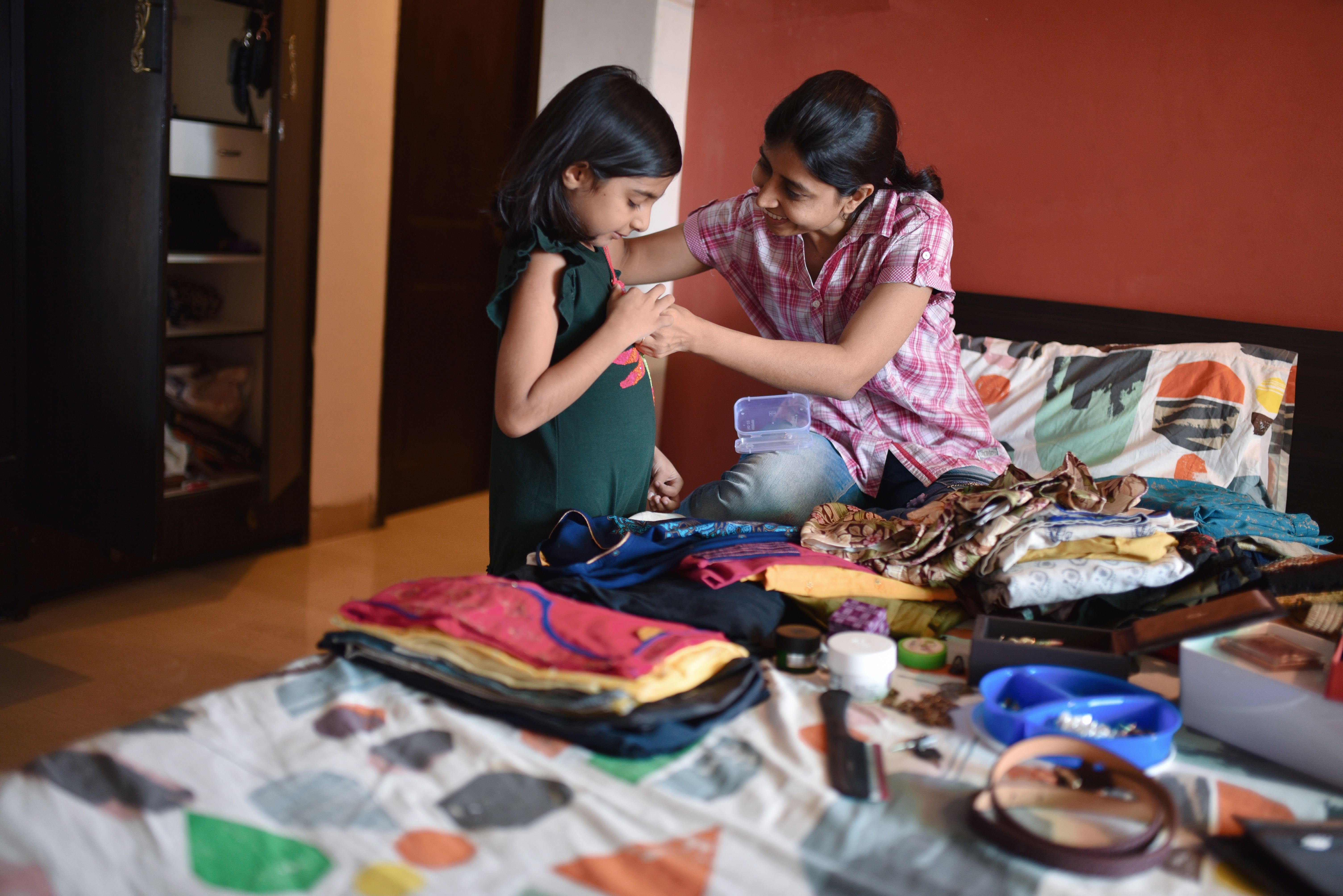 Young girl and adult woman sort clothes in bedroom