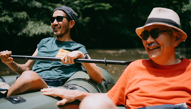 Adult son and older father enjoy floating in a waterway