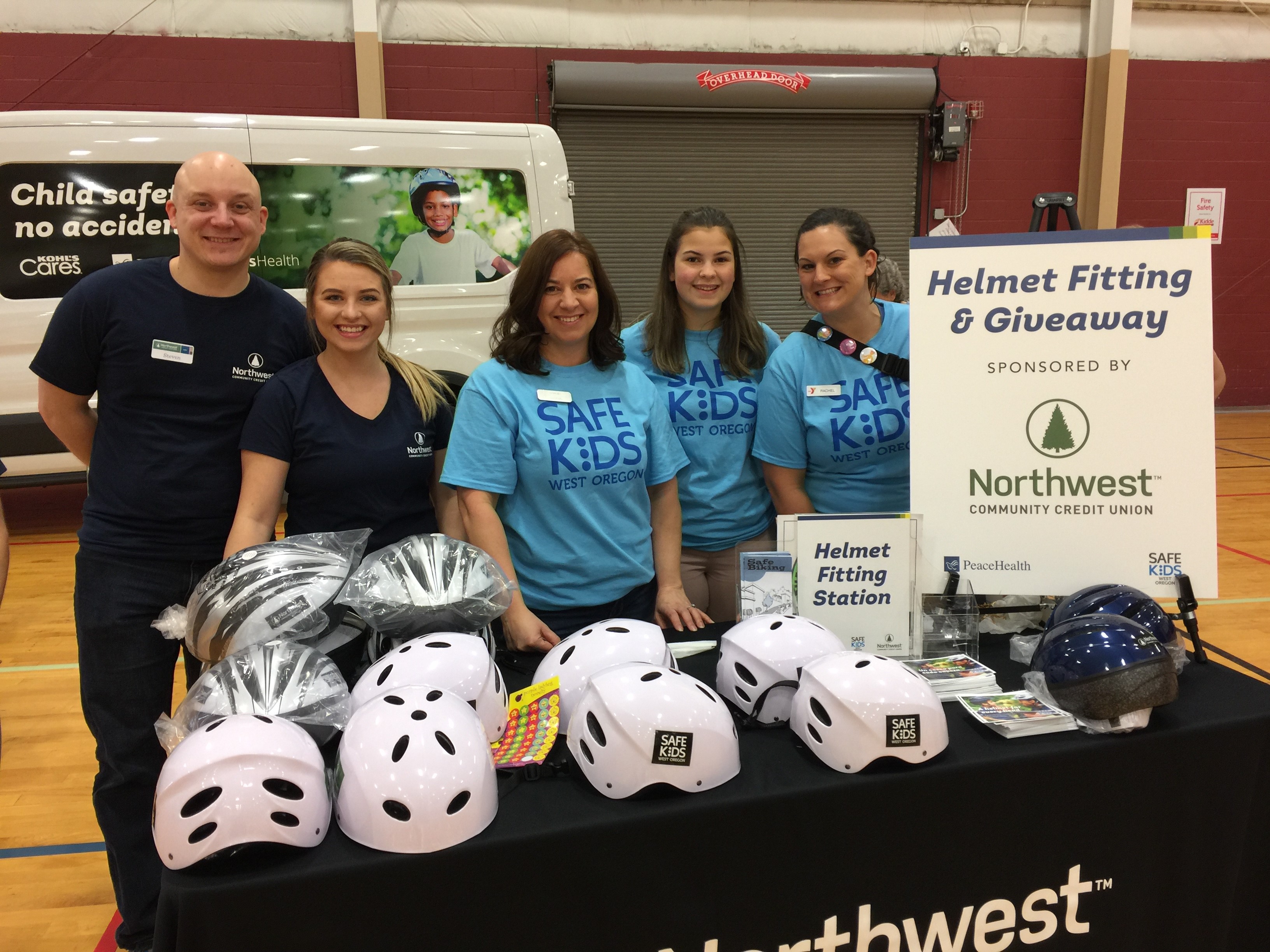 A team of PeaceHealth volunteers smiles at a helmet fitting event for "Safe Kids"