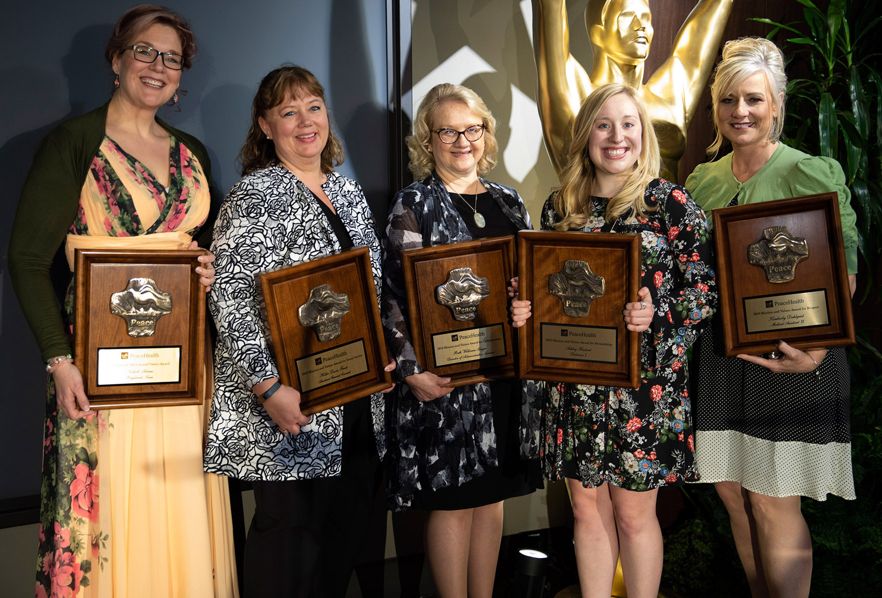 A group of five women hold award plaques