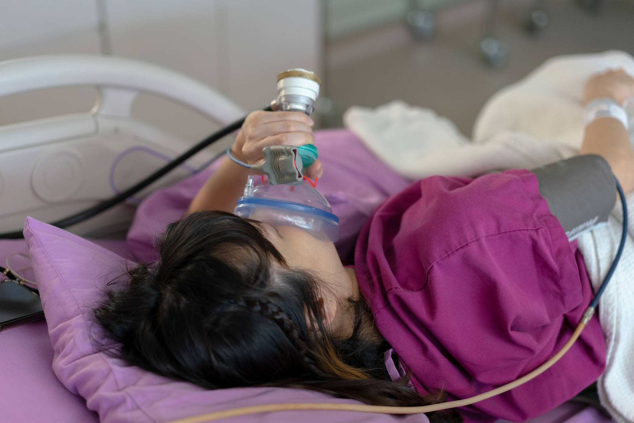 A young patient holds a nitrous oxide mask to her face