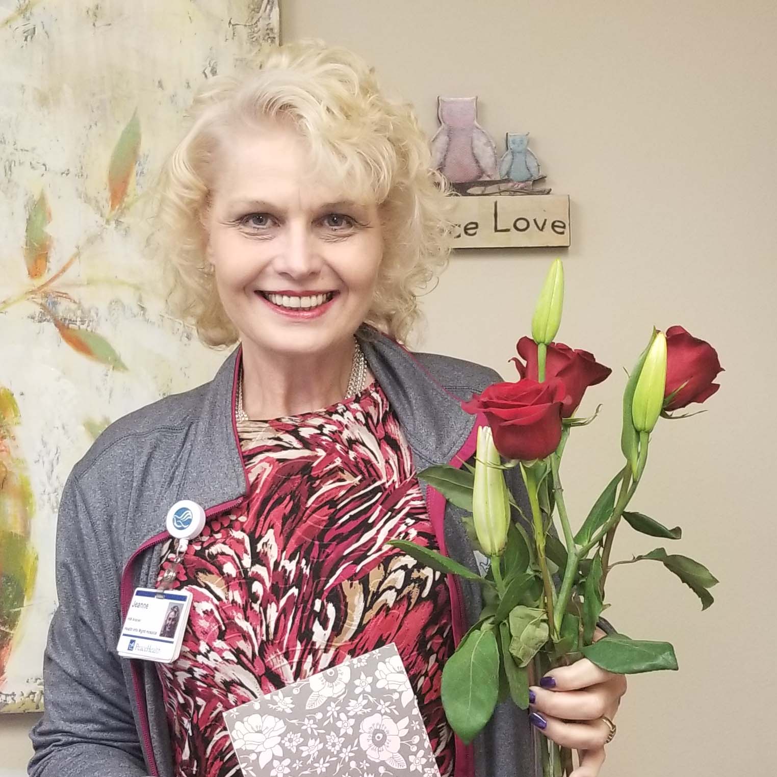 A PeaceHealth staff member holds a bouquet of roses and smiles in appreciation