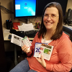 A woman sitting, smiling and holding recipes in her hands.