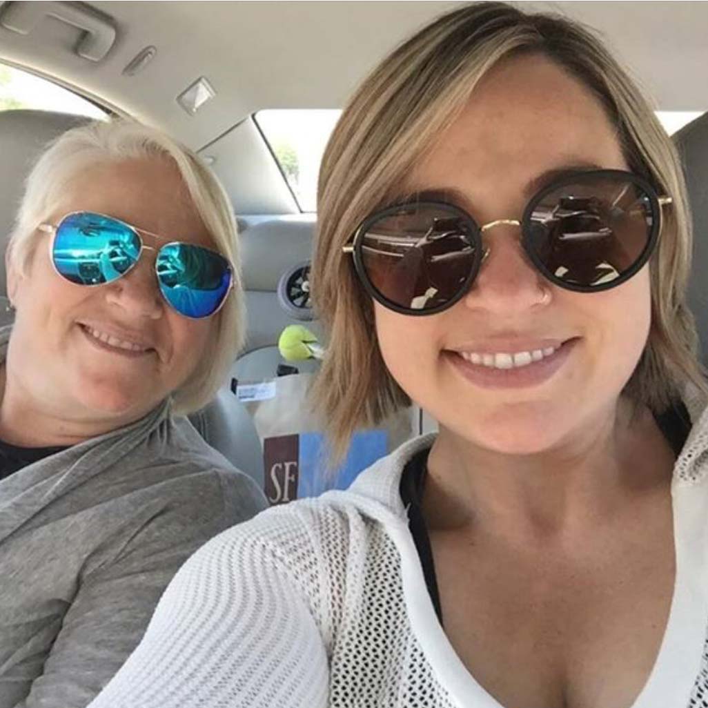 Two people in sunglasses smile in a car