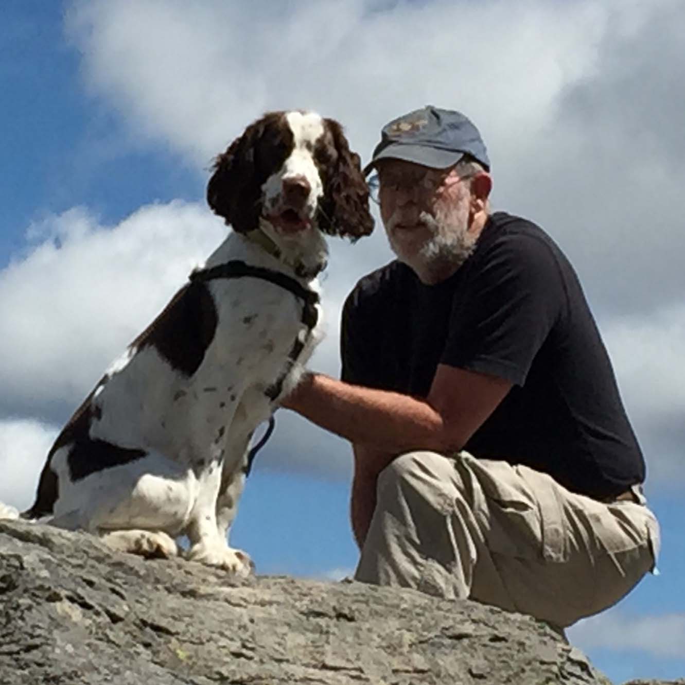 A man and his dog pose for a photo on top of a rock
