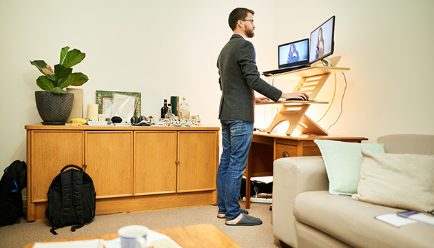 A man uses a standing desk for computer work