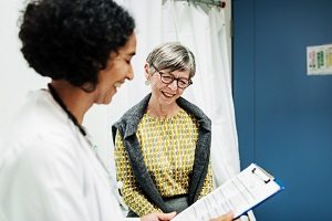 A healthcare provider discusses a chart with a patient in a clinical setting