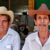 Older Pazsalud men with cowboy hats sitting and facing the camera