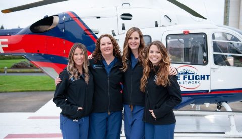 Southwest Medical Center Trauma Physician Assistants stand on the helipad next to a helicopter