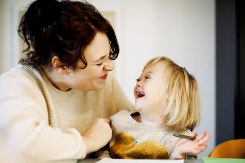 A mother and daughter share a laugh over an art table