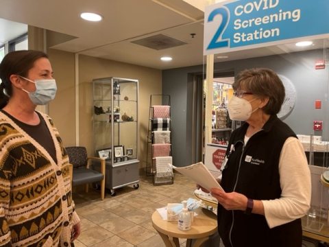 Two people in masks talking in a hospital hallway.