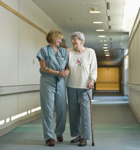 A care provider walks a patient down a medical center hallway