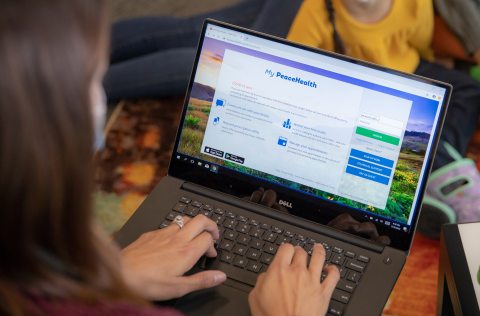 A person on a laptop types while viewing the My PeaceHealth login screen