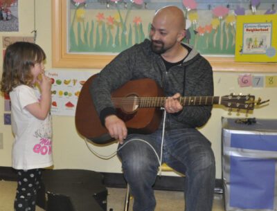 Pat Stack plays guitar for a young girl