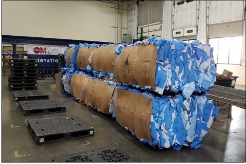 Several bales of blue surgical wrap inside a warehouse