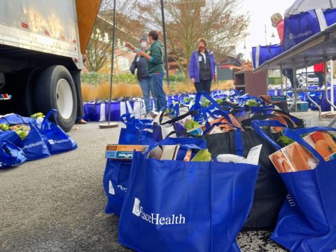 Several blue bags filled with Thanksgiving food wait to be delivered