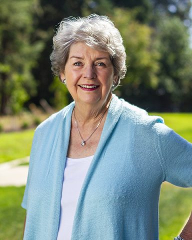 Photo of Karlyn wearing a blue cardigan in front of a grass background