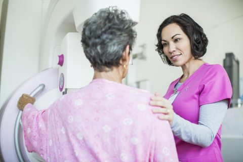 A healthcare provider reassures a patient preparing for a mammorgram