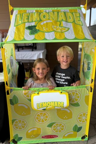 A young boy and girl in a yellow lemonade stand