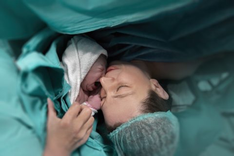 baby being held to mother's face after birth for skin-to-skin bonding