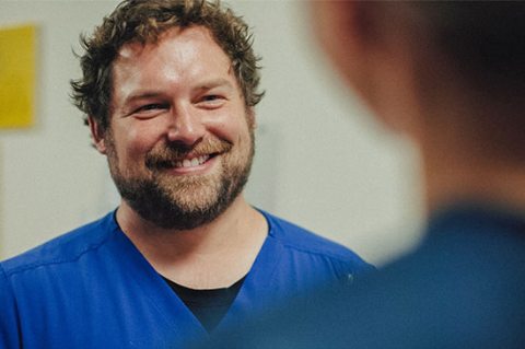 A PeaceHealth nuse smiles while speaking with someone in the foreground