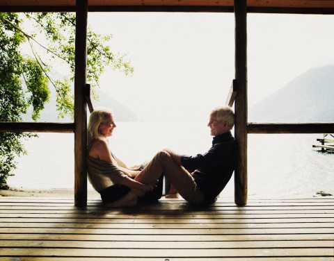 A man and wife sitting on a dock and looking at each other