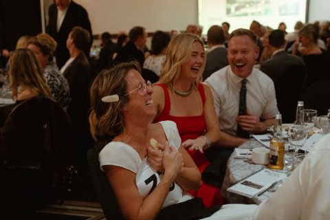 three people laughing at their table during the gala
