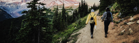 Two people hiking a trail near a mountain