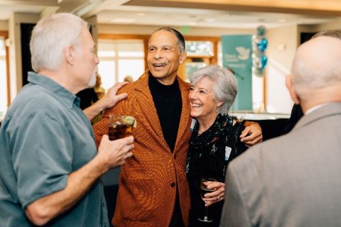 Dr James M Douglas Jr hugging and smiling with peers at his retirement party