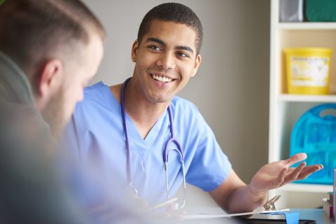 A clinician smiles while talking with a person in the foreground