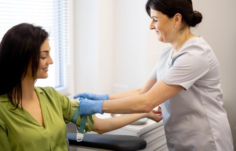 A phlebotomist prepares to draw blood from a patient