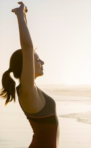 Woman stretching in the sun near the ocean waves