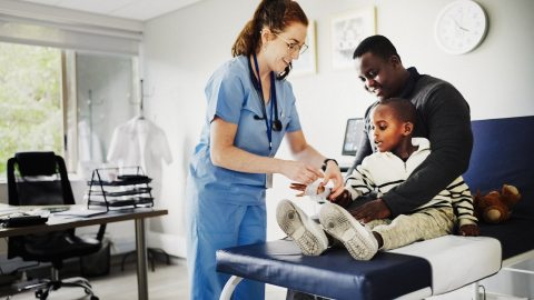 A caregiver assists a young patient and their father in a clinical setting