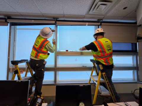 Workers placing temporary covers on west-facing windows in patient rooms and other areas