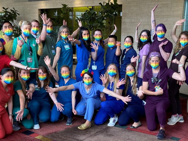 A group of nurses wearing rainbow pride scrubs poses for the camera at Firstenberg Tower