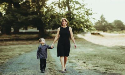 MaryAnn and child walk along a gravel road in a nature-filled area.
