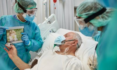 Surgeons show a photo to a patient in a hospital bed