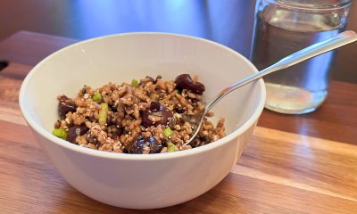 Cherry, quinoa and wild rice salad in white bowl with a glass of water.