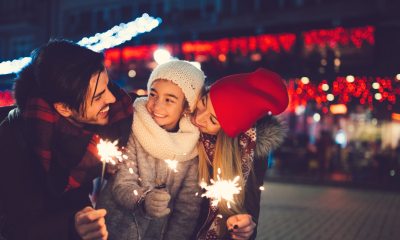 Two adults and young child hold sparklers to celebrate winter holiday