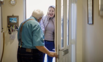 Older man opens door of his home to a happy woman